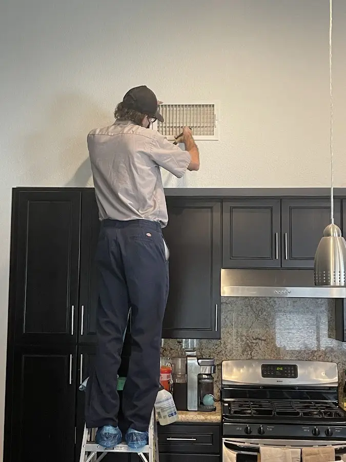 Technician inspecting an air vent during HVAC service in Chickasha